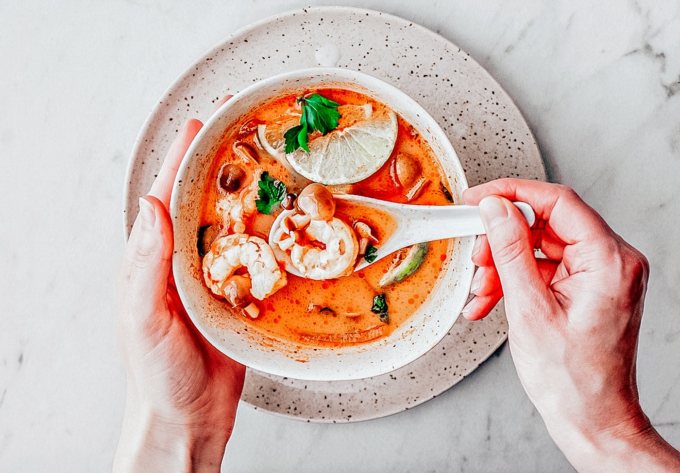 Bowl of soup with hand spooning some broth with a spoon.