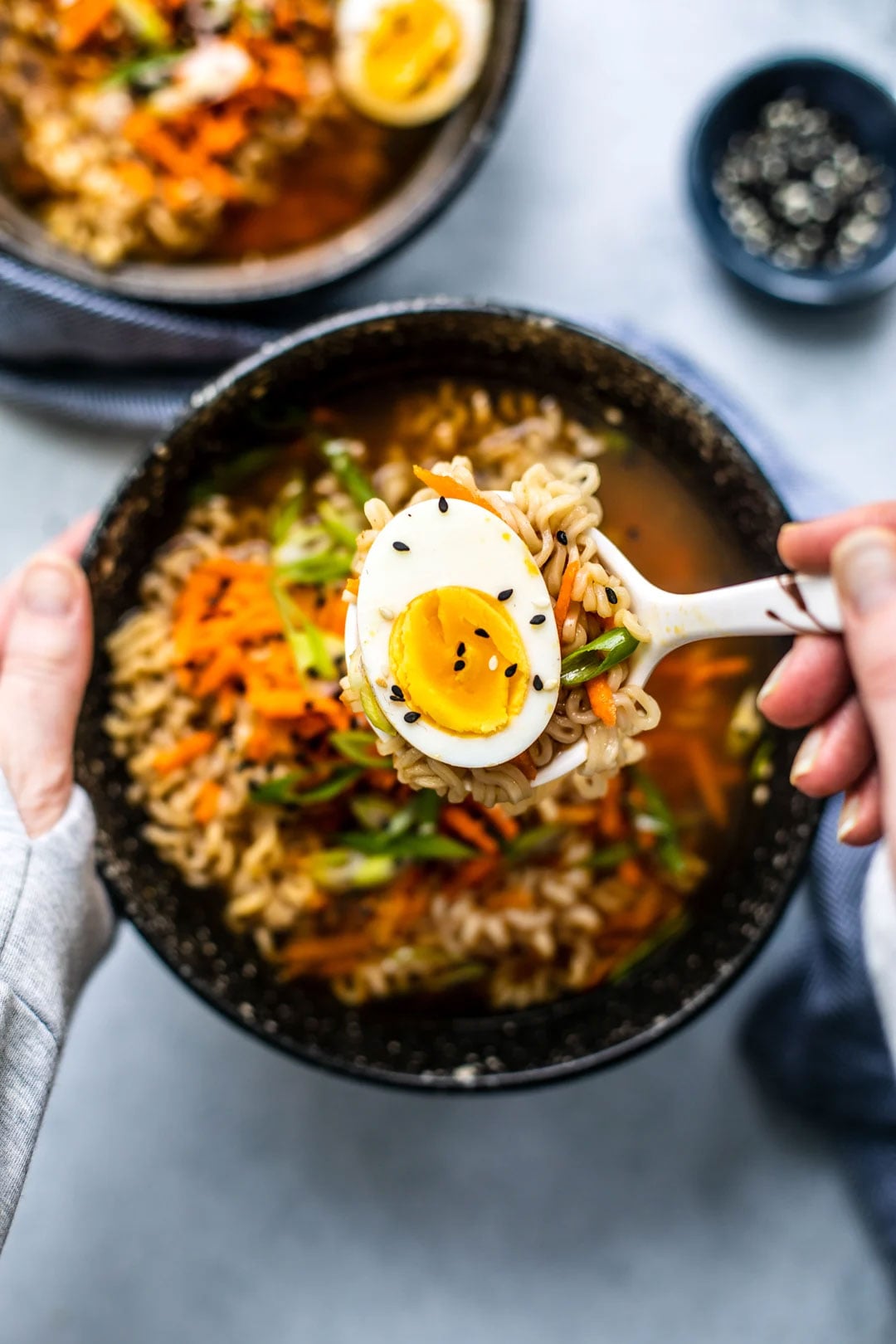 Jammy egg being spooned up from ramen soup bowl.