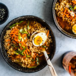 Ramen bowl with soft-boiled egg and a pinch bowl of sesame seeds.