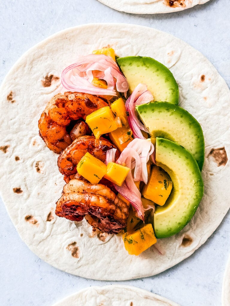 Flour tortilla topped with juicy shrimp, mango salsa, pickled onions, and avocado.