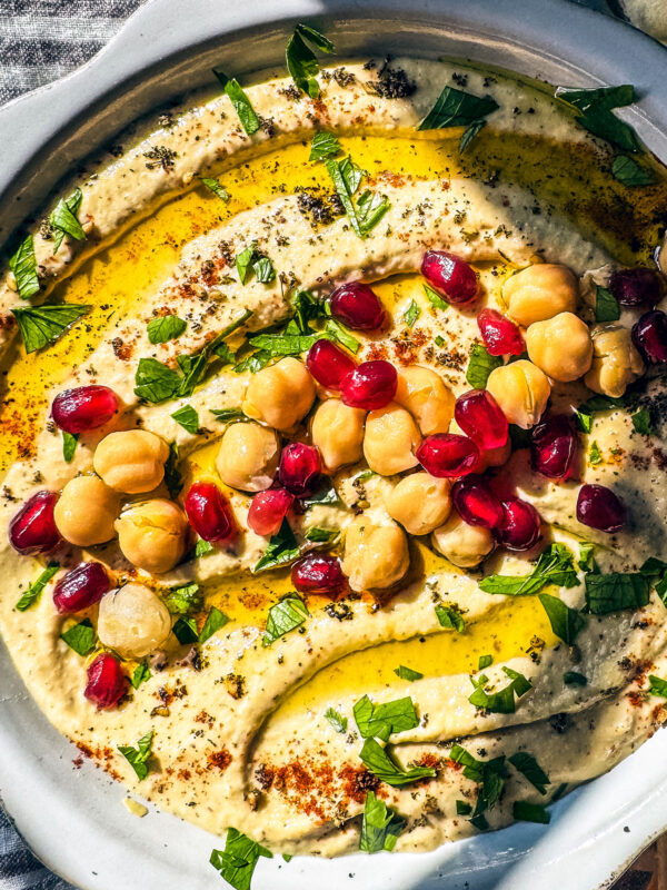 Homemade hummus topped with olive oil, chickpeas, and pomegranate arils.