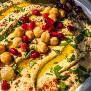 Homemade hummus topped with olive oil, chickpeas, and pomegranate arils.