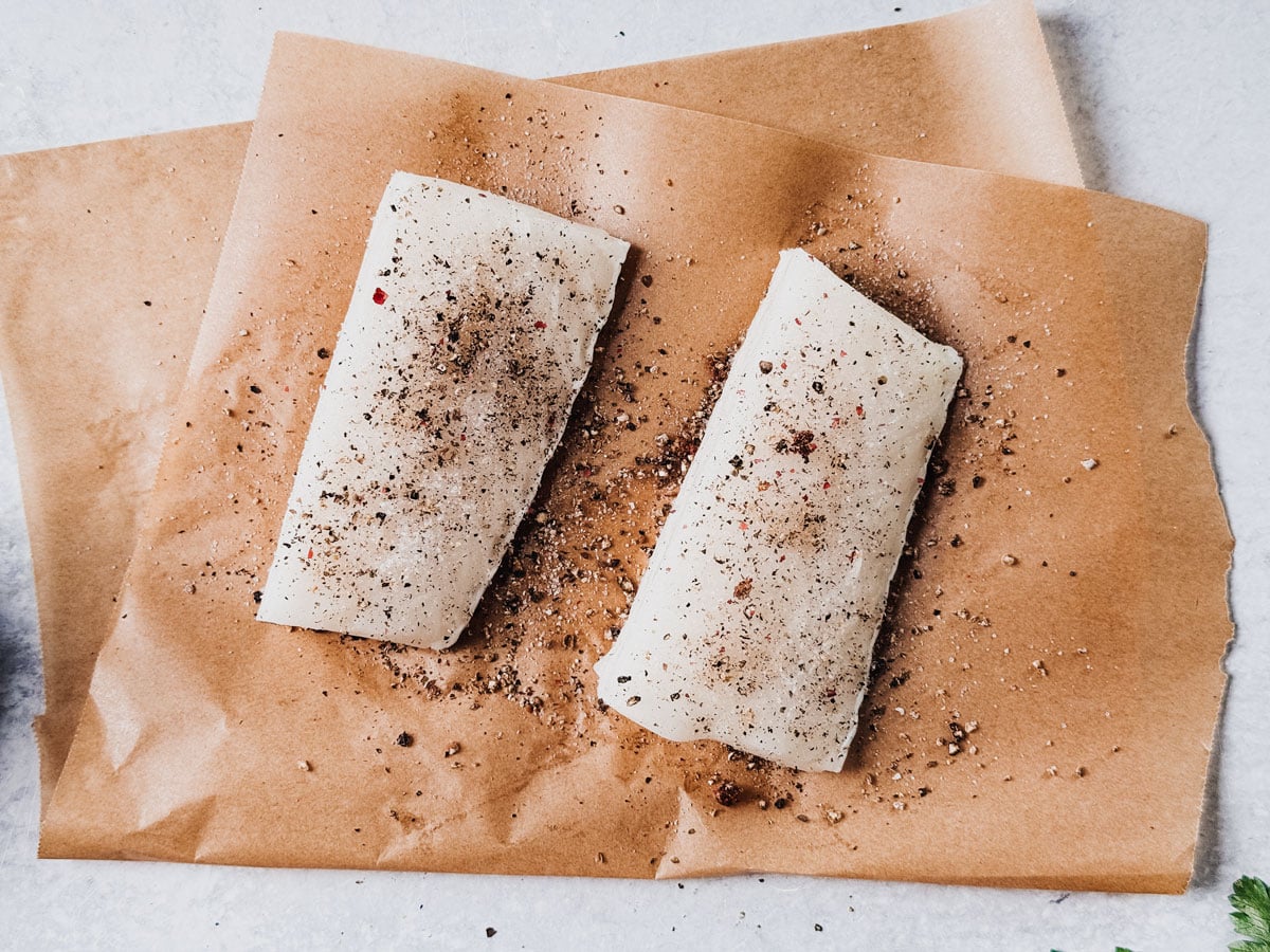 Sea bass fillets, uncooked, seasoned with salt and pepper.