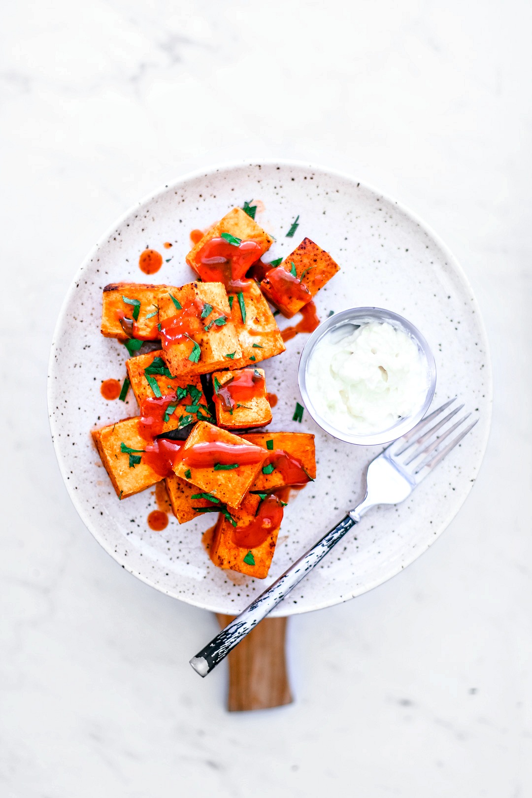 Crispy Buffalo Tofu Bites With Garlicky Yogurt + Feta Dip on a plate