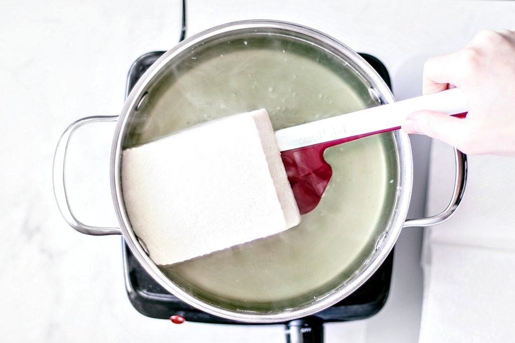 Tofu being removed from boiling water.