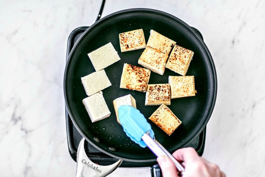 Tofu being pan-fried to a crisp.