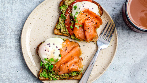 Slices of toast on a plate with smoked salmon, avocado, and poached eggs.