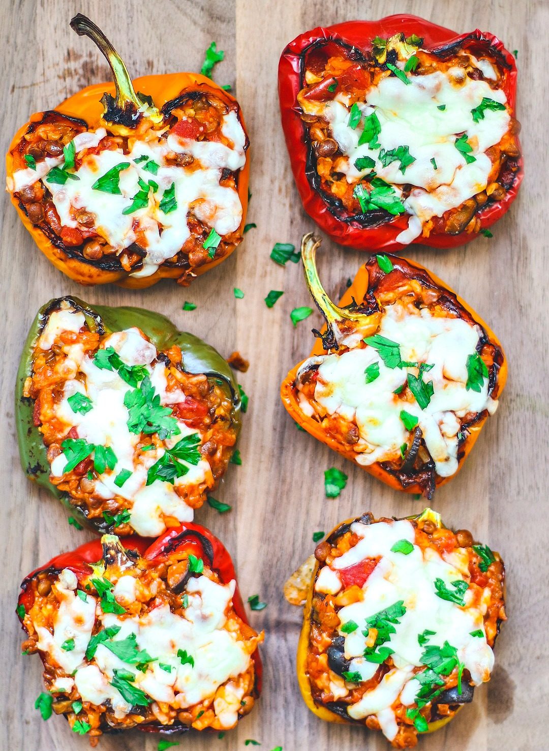 Stuffed peppers on a platter covered in cheese.