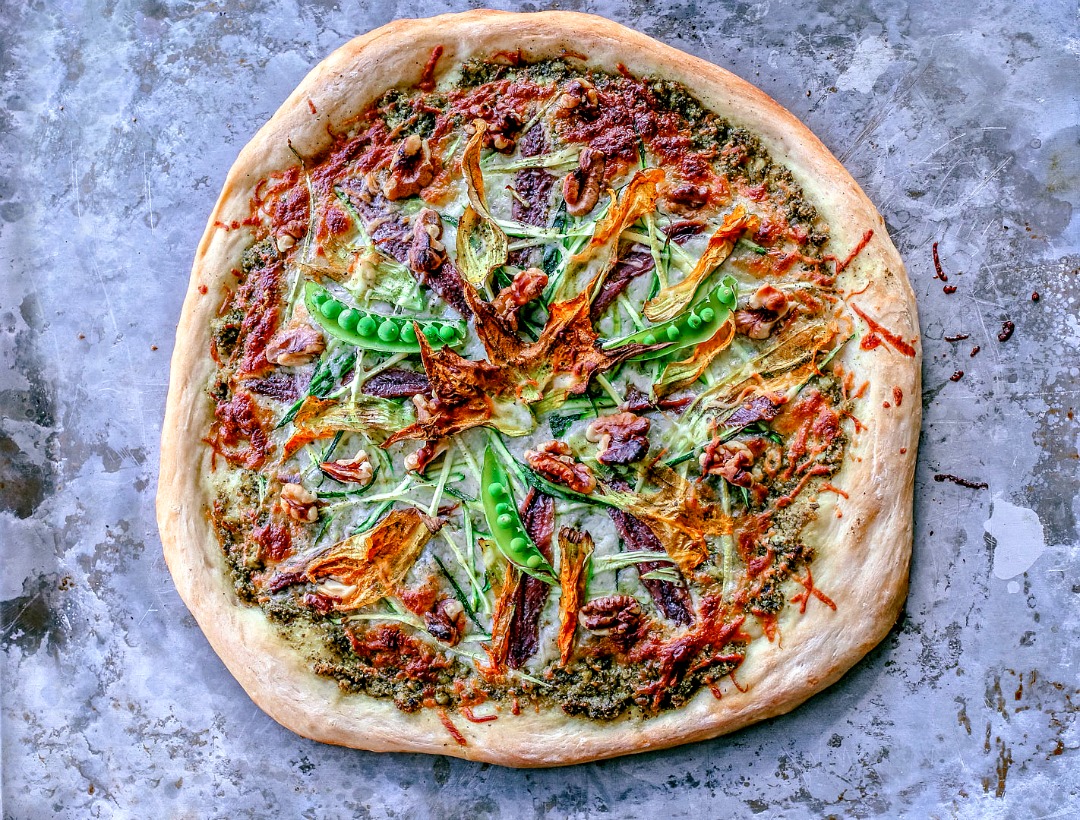 summer zucchini and pesto pizza with squash blossoms