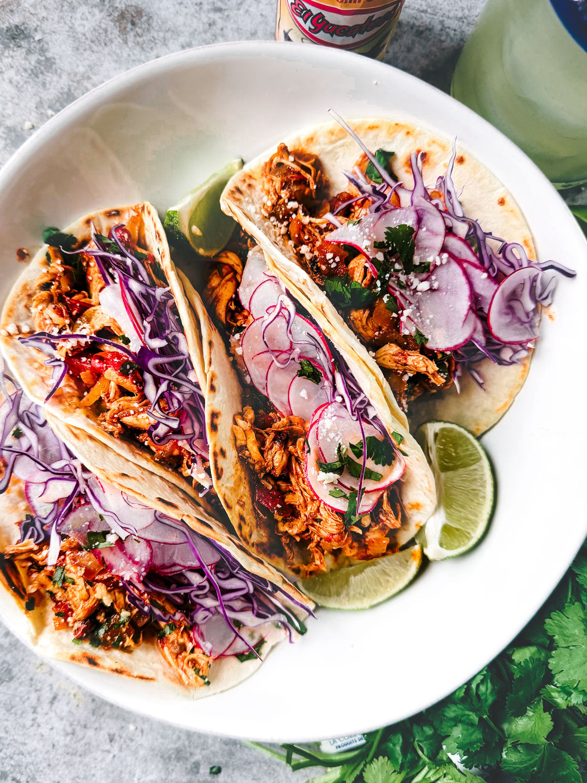 Shredded chicken tacos folded into a serving bowl.