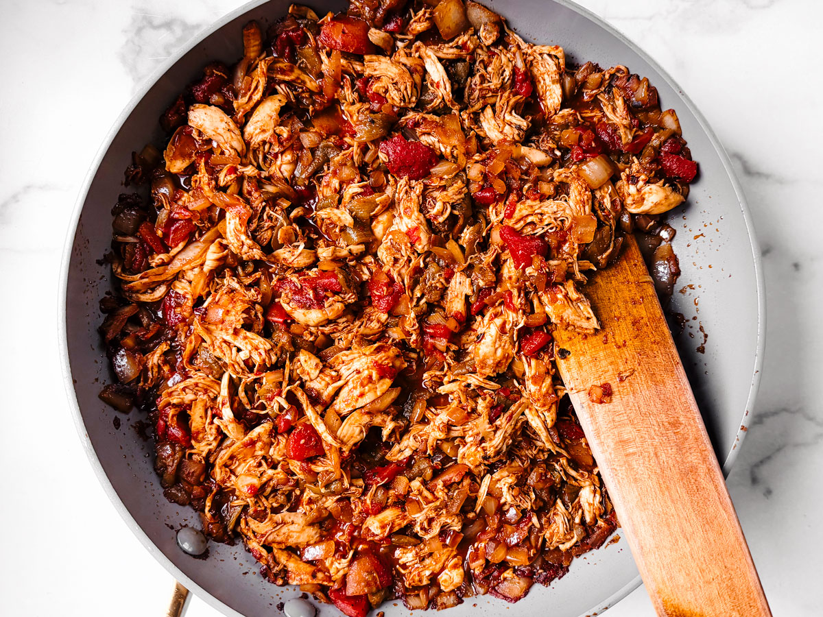 Saucepan with shredded chicken tossed in the tomato sauce.