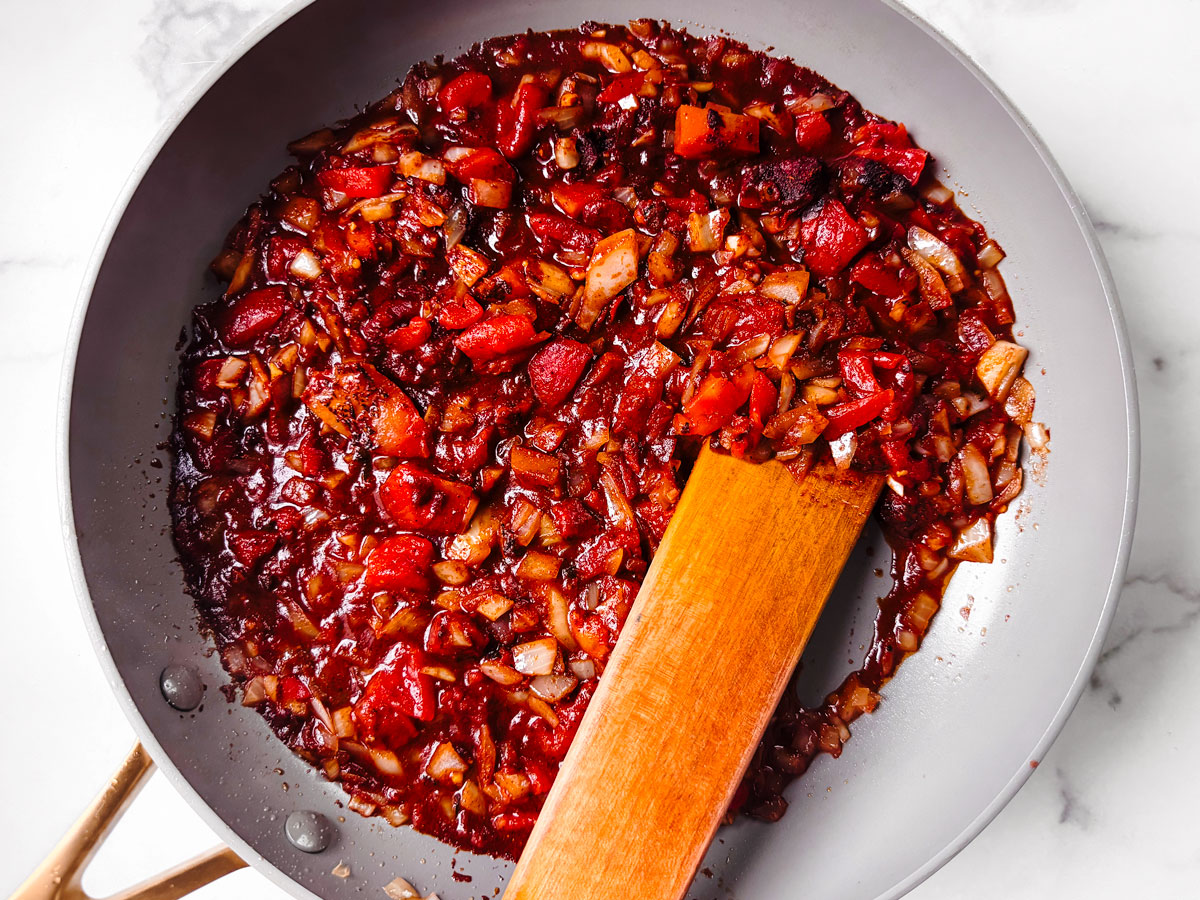 Saucepan with seasoned tomatoes and onions.