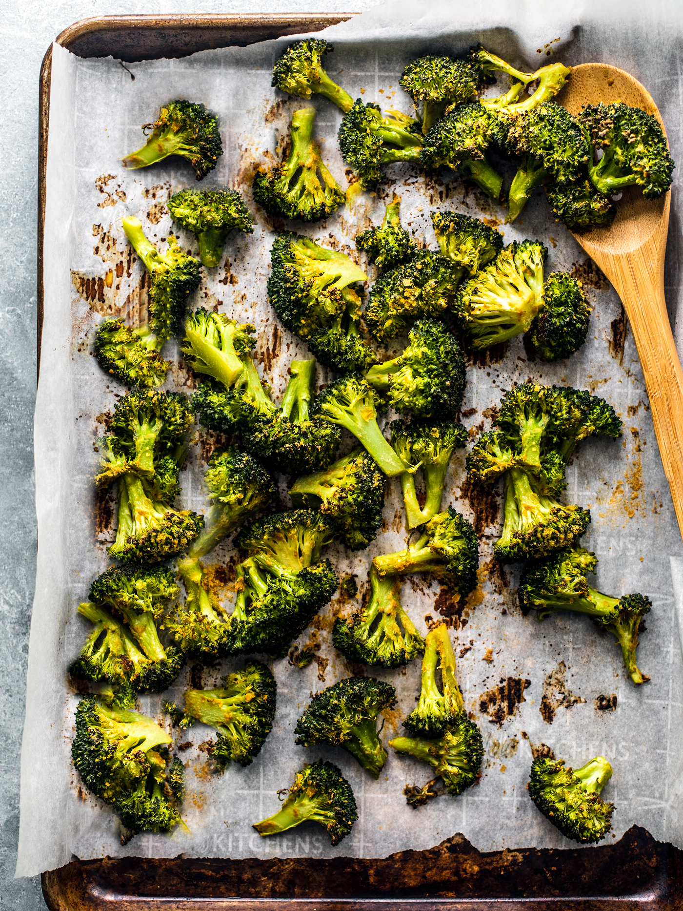 Sheet pan covered with parchment and roasted broccoli florets.
