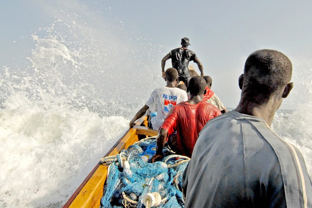 Fishermen in small boat with nets in shaky water