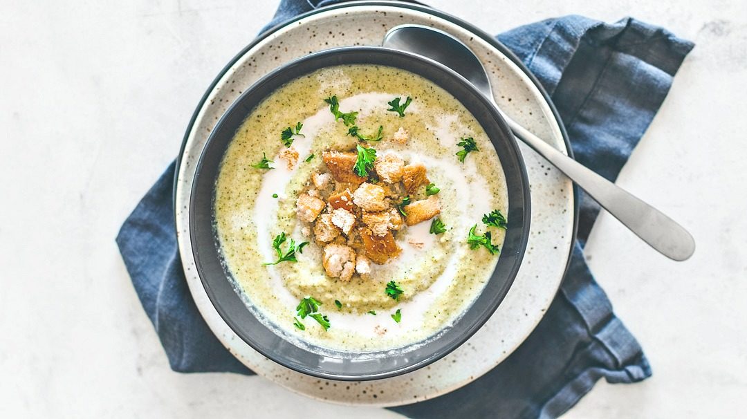 Bowl of cream of broccoli soup garnished with croutons.