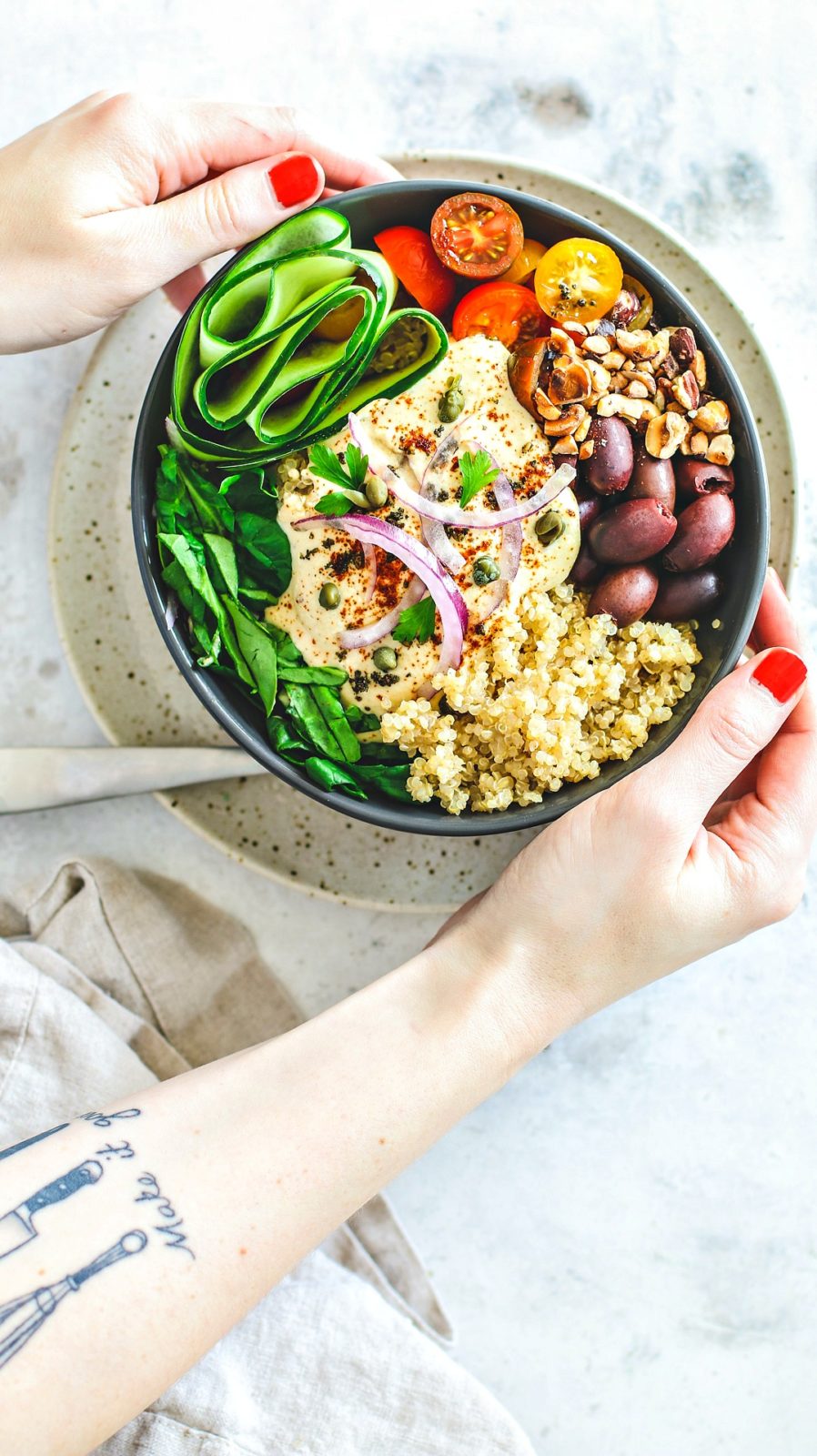 Hands holding bowl of Mediterranean Quinoa Salad