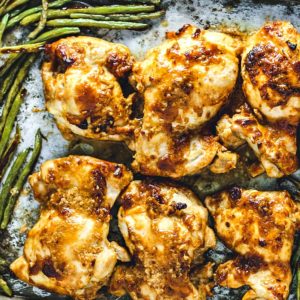 Chicken Thighs slathered in peanut sauce on a sheet pan with green beans.