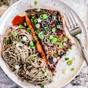 Hot Honey and Soy Salmon on a plate with soba noodles and scallions.