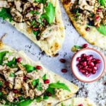 Naan breads topped with hummus, chicken, and greens.