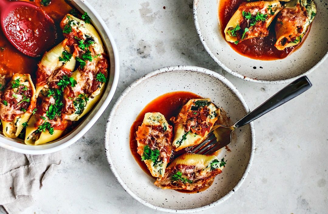 Stuffed pasta shells served in bowls with sauce.