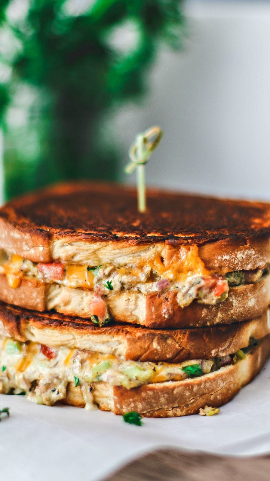 Close up of Cheddar Jalapeño Gourmet Grilled Cheese sandwiches stacked on top of one another in a melted mess.