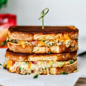 Cheddar Jalapeño Gourmet Grilled Cheese sandwiches stacked on top of one another in a melted mess.