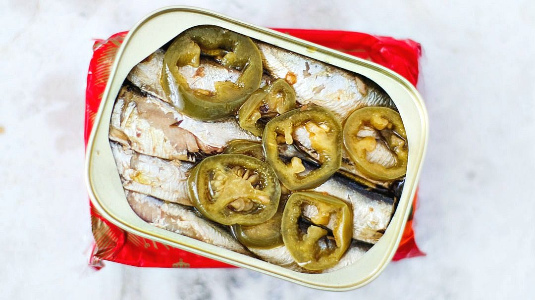 Opened can of King Oscar sardines with slices of jalapenos.
