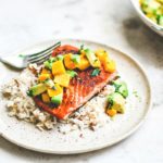 Pan-Seared Salmon on plate over rice and topped with mango and avocado salsa.