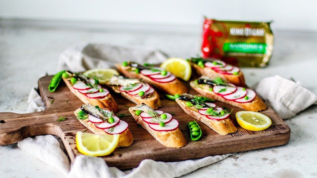 Colorful canapés topped with radishes, peas, sardines, and dill.