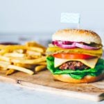 Stacked beef burger on a platter with fries.