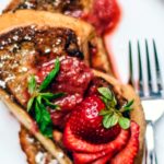 Close up of fresh strawberries fanned over French toast.