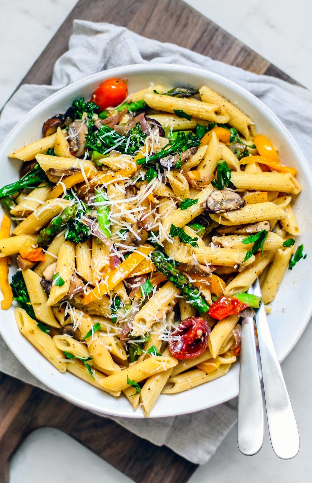 A big colorful serving bowl full of pasta and vegetables.