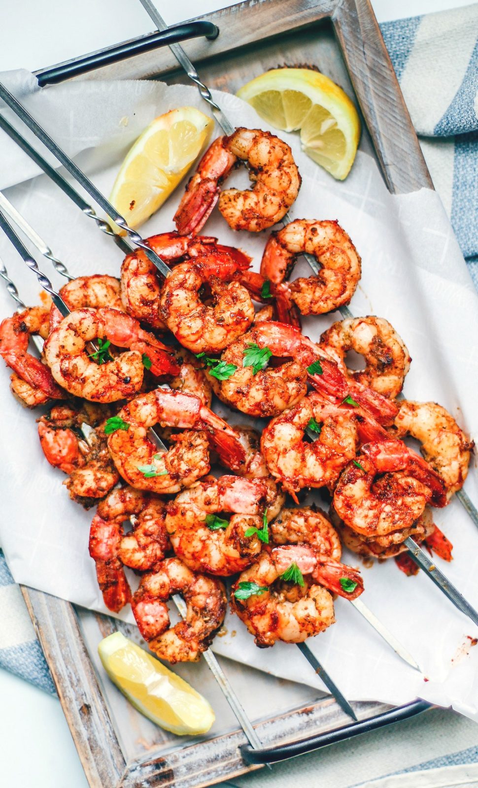 Tray of grilled shrimp skewers with lemon wedges.