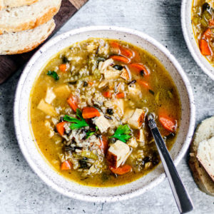 A bowl of turkey and wild rice soup with slices of fresh bread.