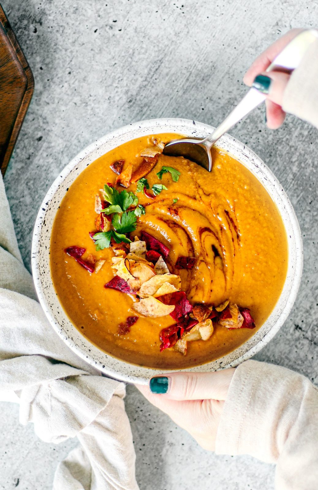 Hands holding bowl of sweet potato soup.