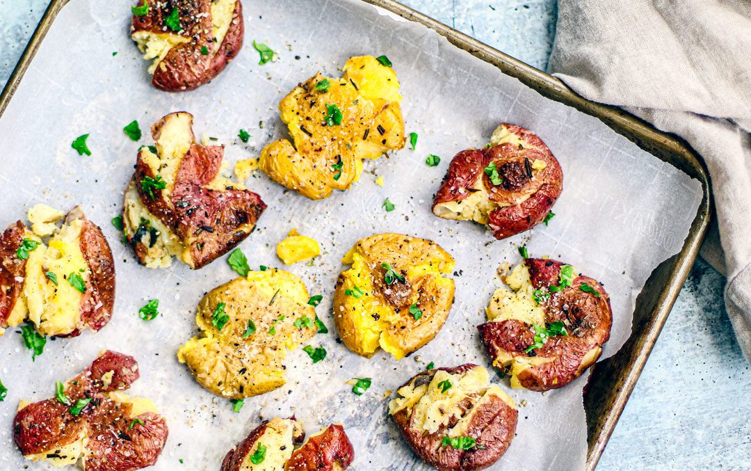 Baking dish full of smashed potatoes.