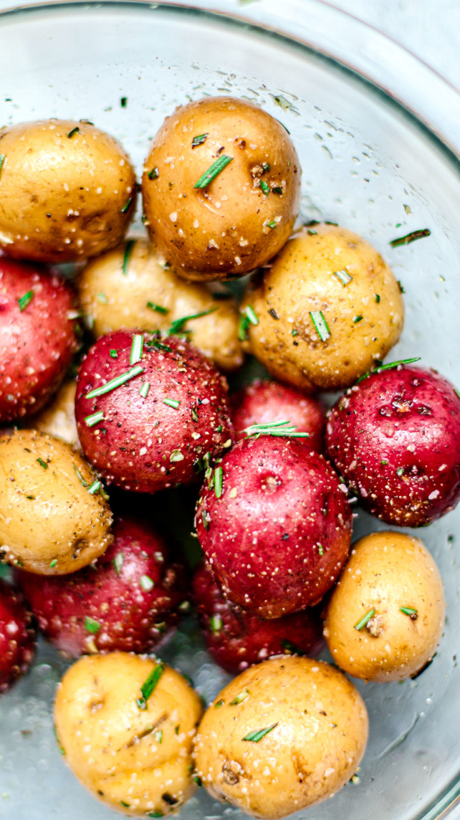 Bowl of potatoes with olive oil and rosemary.