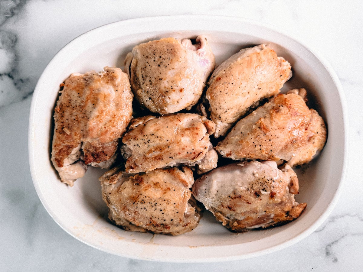 Seared chicken thighs in a serving dish.