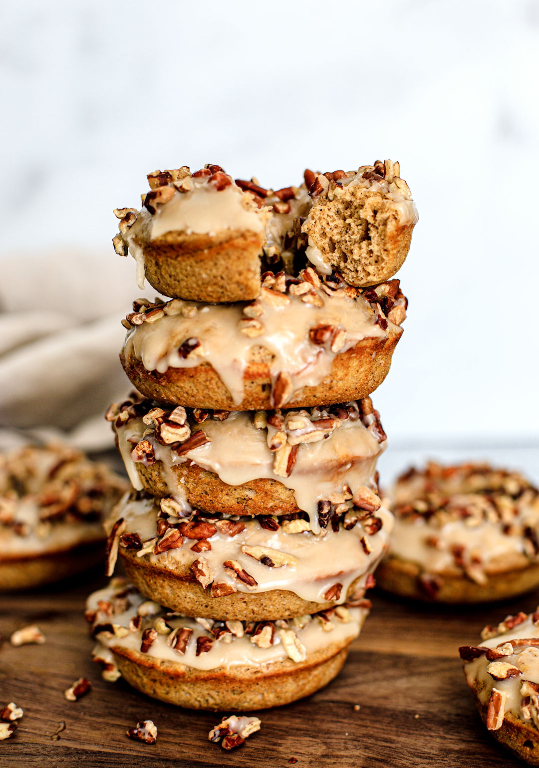Stack of maple baked donuts; one has a bite in it.