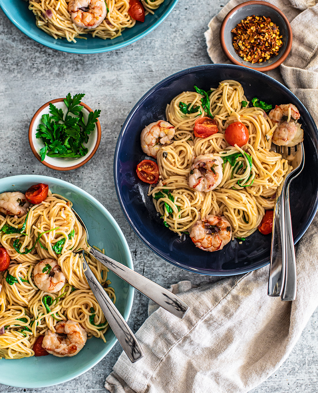 Tablescape with three plates of shrimp scampi.