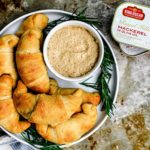 Plate of cheesy crescent rolls with can of King Oscar Mackerel next to it.