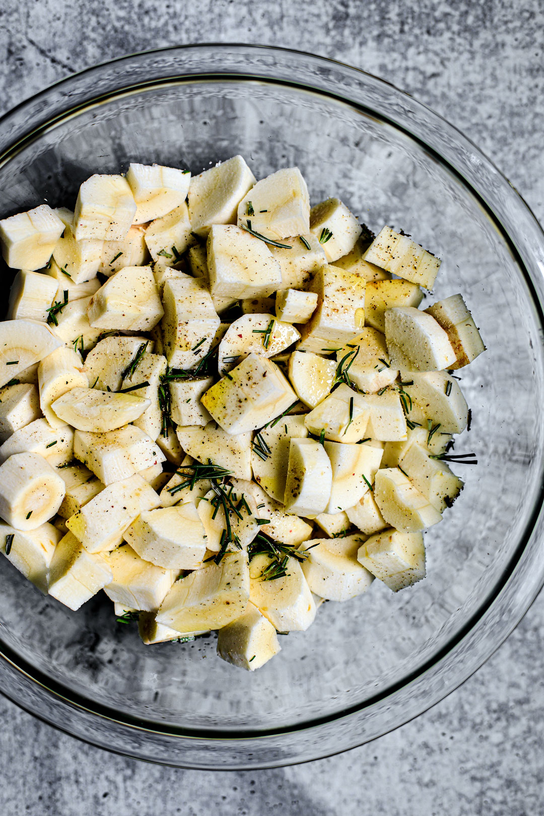 Bowl of cubed parsnips with olive oil and rosemary.