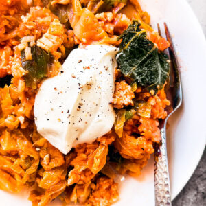 Plate of unstuffed cabbage rolls with a dollop of sour cream.