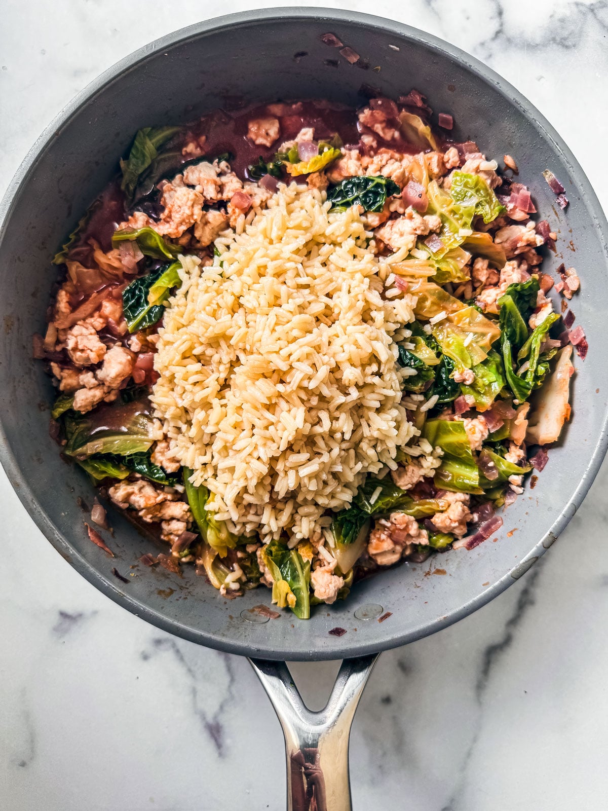 Cooked rice added to the skillet of meat and cabbage.