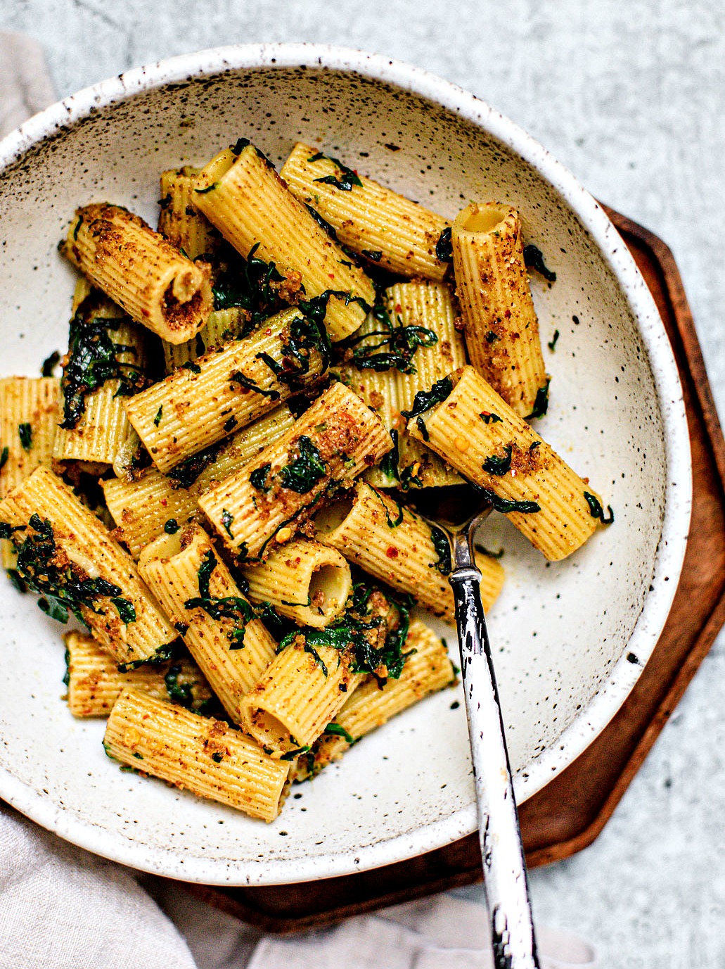 Close up of bowl full of garlicky rigatoni pasta with spinach.