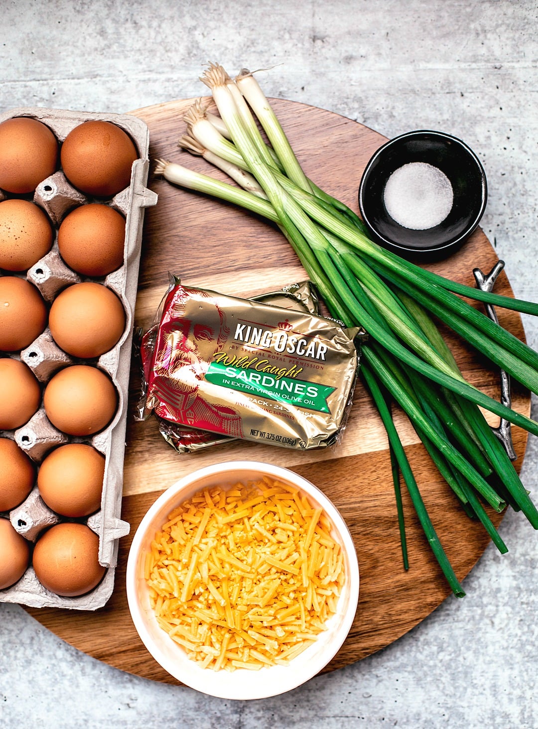 Ingredients for egg muffins on a round wooden board.
