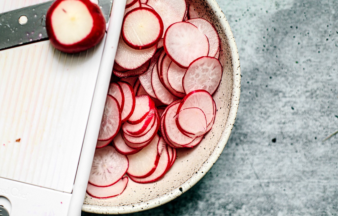 Bowl of thinly sliced radishes with a mandolin.