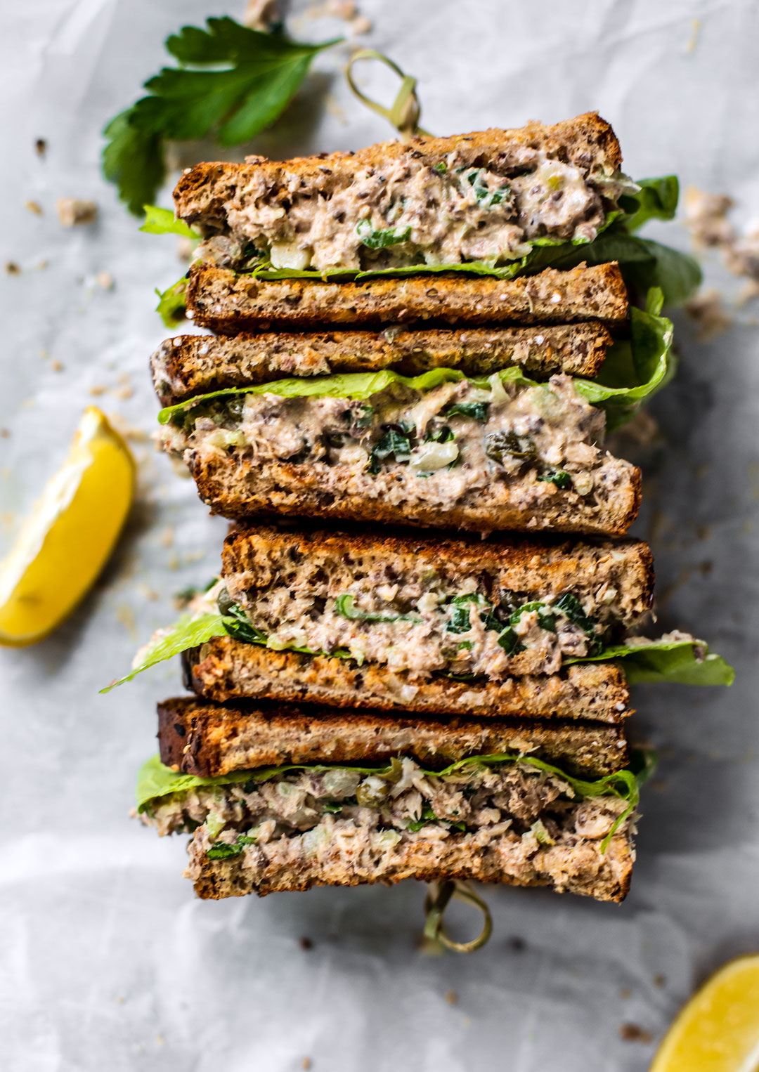 Spicy spanish sardine sandwiches sliced in half and stacked with lemons on the sides.