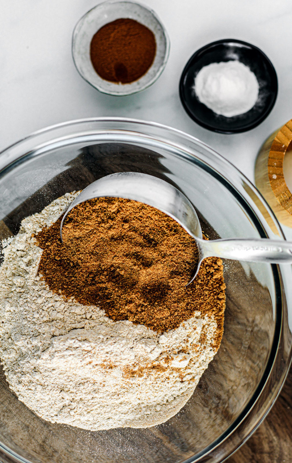 Mixing bowl with whole wheat flour and coconut palm sugar in it with pinch bowls off to the side.