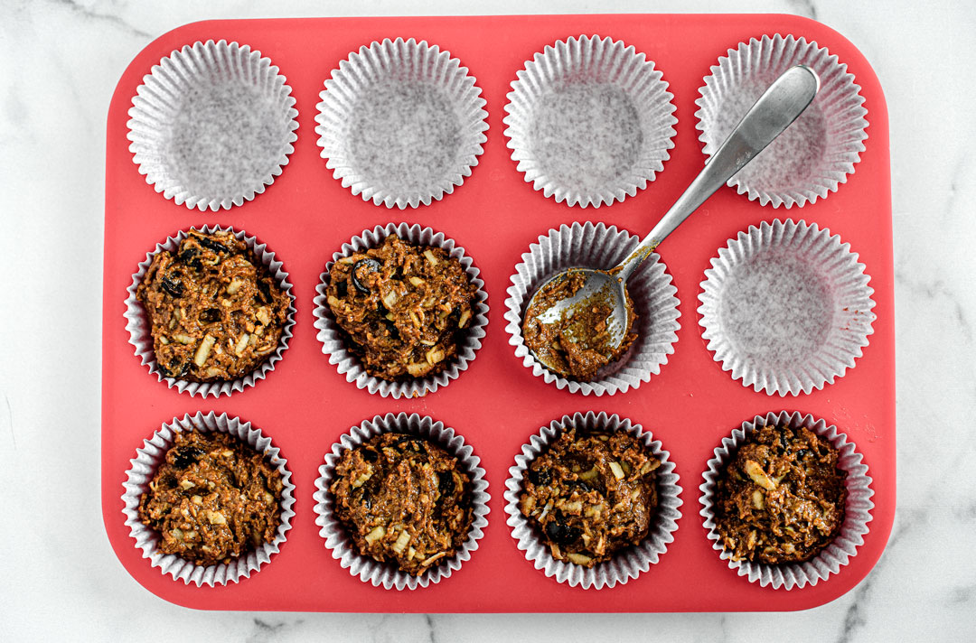 Muffin cups placed in a silicone muffin tray. Half of the muffin cups are filled with cupcake batter.